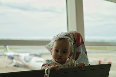 Close-up of boy looking through airplane window