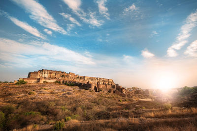 Rock formations on landscape against cloudy sky