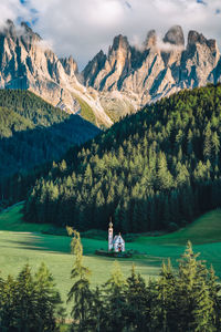 People sitting by lake against mountains