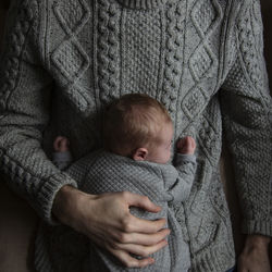 Directly above shot of father holding baby while lying on bed