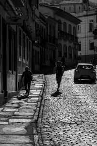 Rear view of people walking on street amidst buildings in city