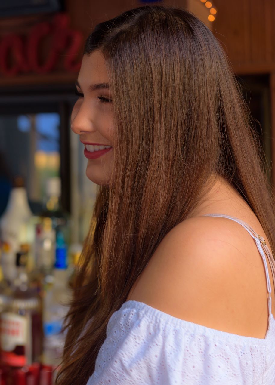 long hair, hairstyle, one person, young women, hair, women, real people, lifestyles, leisure activity, focus on foreground, brown hair, young adult, smiling, portrait, headshot, indoors, adult, looking, happiness, beautiful woman, teenager