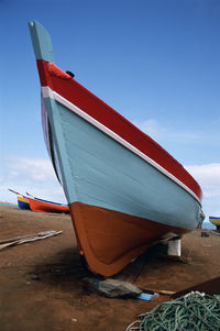 Boat moored on beach against sky