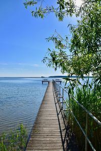 Wooden railing by sea against sky