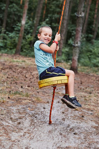 Boy sitting on swing at playground