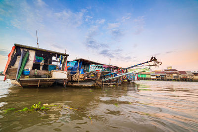 Fishing boats moored at shore against sky