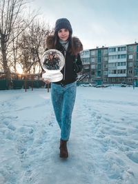 Portrait of young woman standing on snow covered field