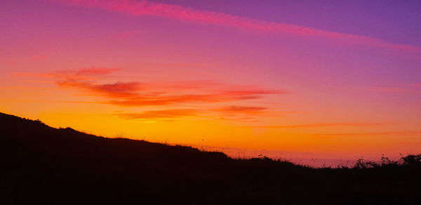 Scenic view of dramatic sky over silhouette landscape