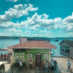 People in sea by buildings against sky