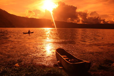 Silhouette boating in calm lake at sunset