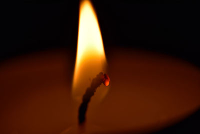 Close-up of lit tea light candle in dark room