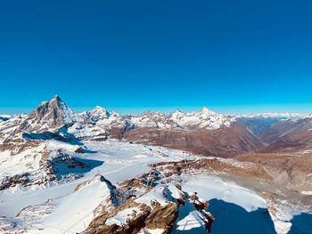 Scenic view of snowcapped mountains against clear blue sky