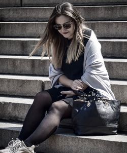 Young woman wearing sunglasses sitting on staircase