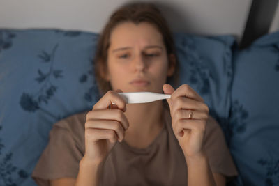 Sick woman checking temperature at home