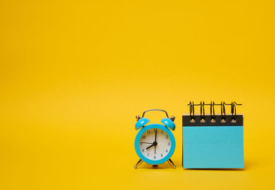 Close-up of alarm clock against yellow background