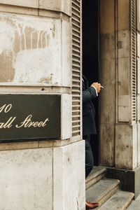 Midsection of man smoking cigarette standing by building