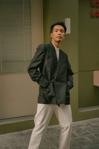 Portrait of businessman standing against wall