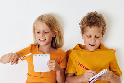 Sibling writing in diary against white background