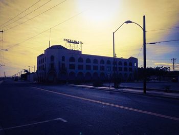 Road passing through city at sunset