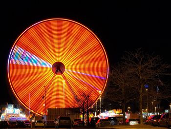 Illuminated ferris wheel against sky at night