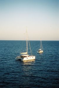 Sailboat sailing on sea against clear sky. shot on 35mm cinestill 50d film. 