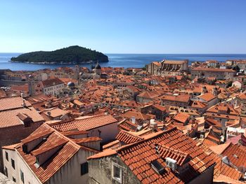 High angle view of townscape by sea against clear blue sky