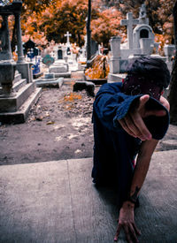 Full length of woman sitting at cemetery