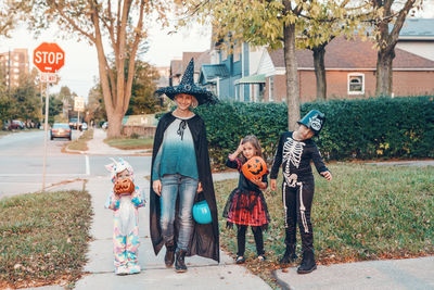 Mother and kids wearing costume standing outdoors