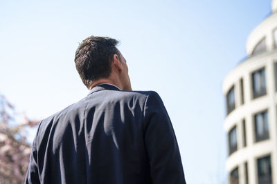 Businessman looking at building on sunny day