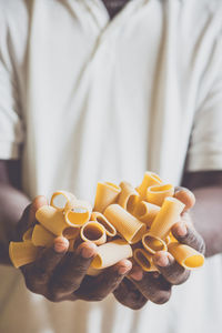 Midsection of man holding fresh pasta in factory