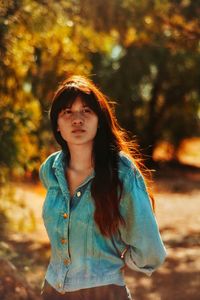 Beautiful young woman standing on field during sunny day