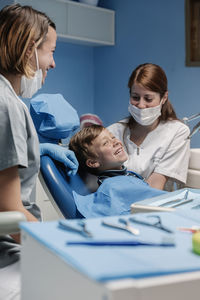 Dentist operating smiling boy in medical clinic