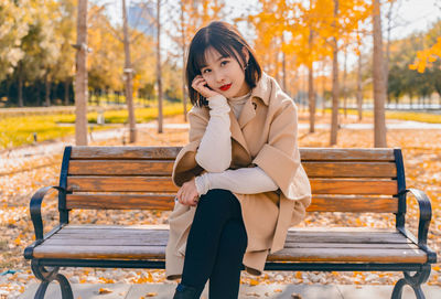 Portrait of beautiful woman sitting on bench in park