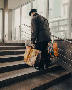 Rear view of man walking on staircase in city