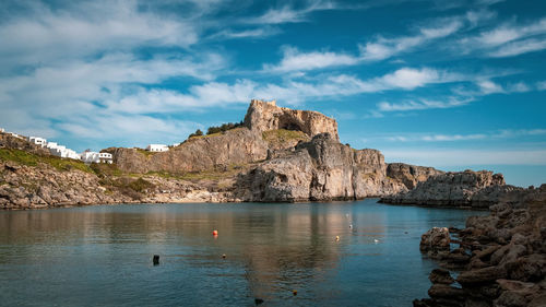 Scenic view of rocks by sea against sky