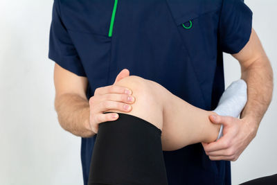 Doctor or physiotherapist working examining treating injured leg of athlete male patient