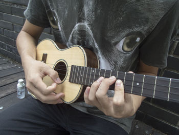 Midsection of man playing ukulele