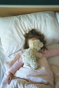 Girl lying on bed with stuffed toy at home