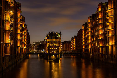 Illuminated wasserschloss, speicherstadt hamburg at sunset with lights reflecting in the water