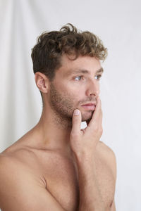 Portrait of shirtless man looking away against white background