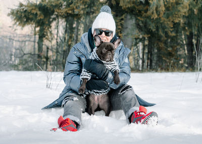 Woman and dog sitting in snow