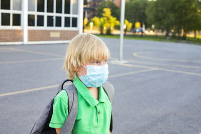 Portrait of boy standing on road in city