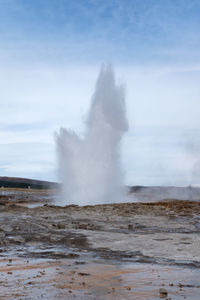 Water spraying against sky