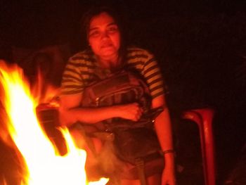 Young man standing against fire at night