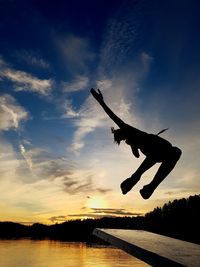 Silhouette man jumping against sky at sunset