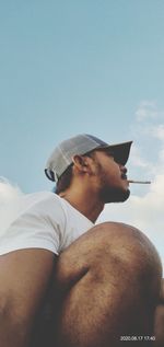 Low angle view of shirtless man looking away against sky