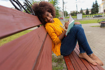 Young woman using mobile phone while sitting outdoors