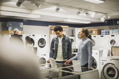 Mature owner talking to male customer in electronics store