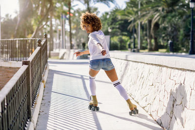 Full length portrait of young woman roller skating on bridge