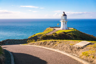 Lighthouse by sea against sky